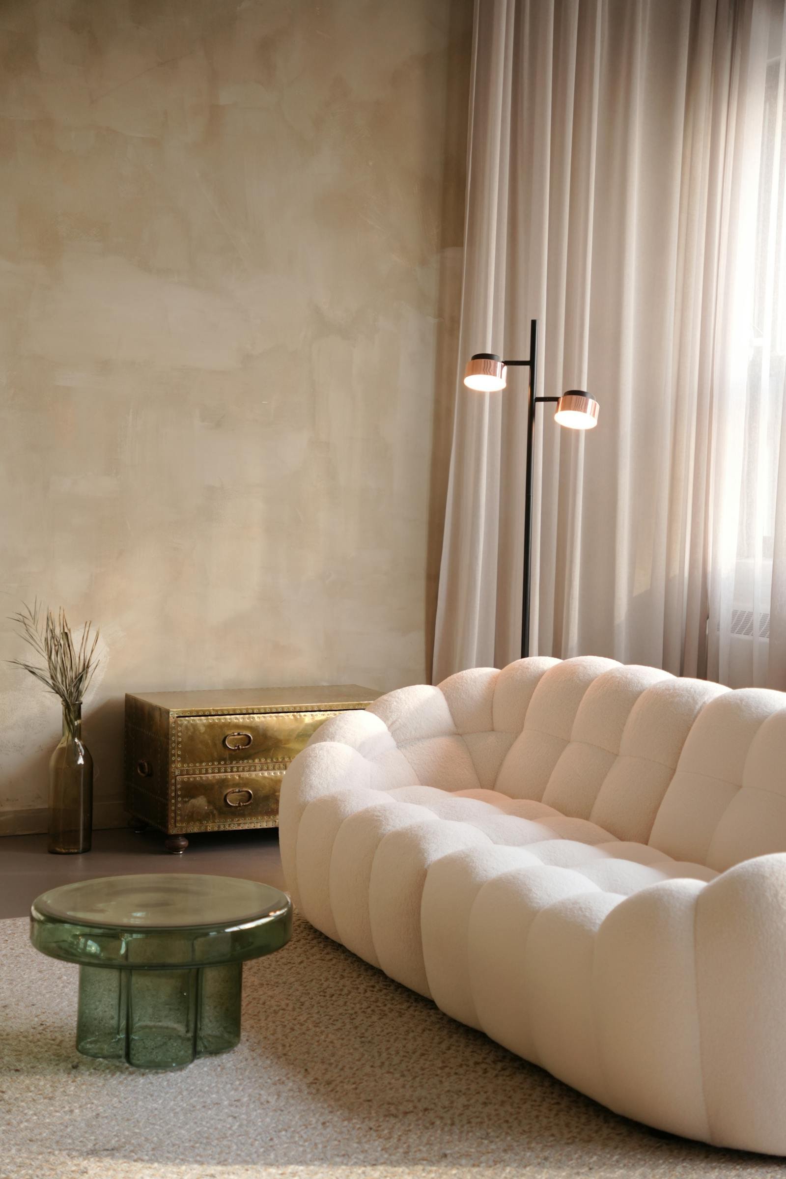 Sala de estar em estilo Japandi com sofá bouclé claro, paredes texturizadas e iluminação suave